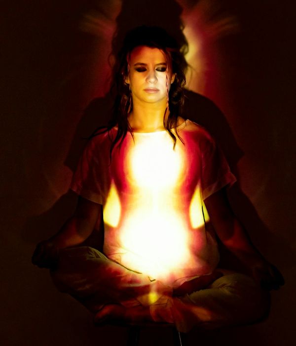 Woman in a calm yoga pose, surrounded by a serene and light atmosphere.